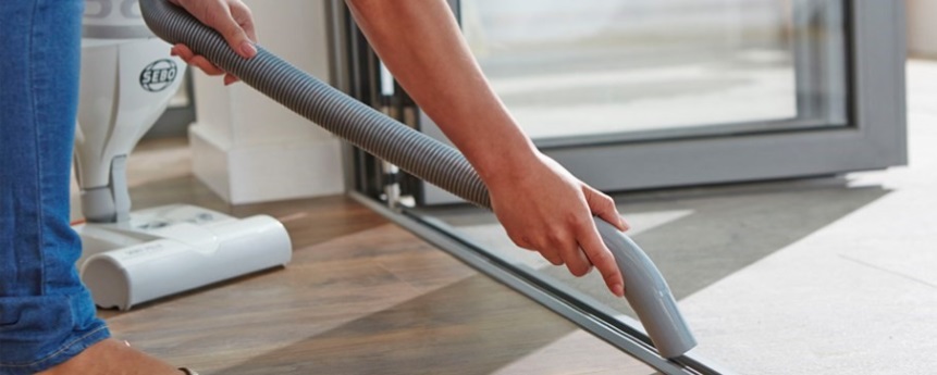 Person vacuuming/cleaning bifold door track to ensure good movement.