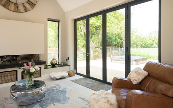 A brown armchair placed in front of a set of bifold doors leading into a garden