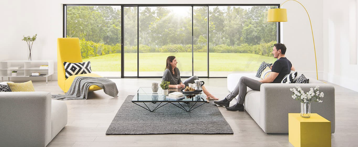 Living room with yellow furniture and black bifold doors leading to a large garden