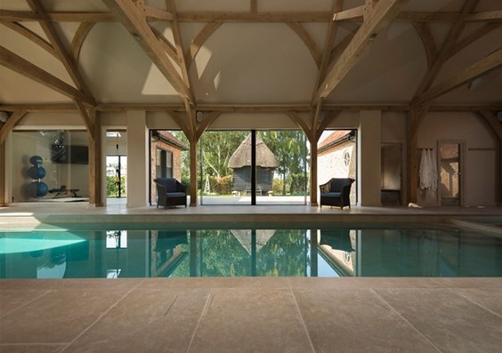 A view of an indoor pool looking out through bifold doors into a garden