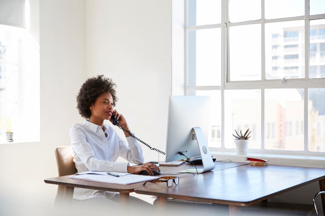 Young Black woman at her desk talking on the phone